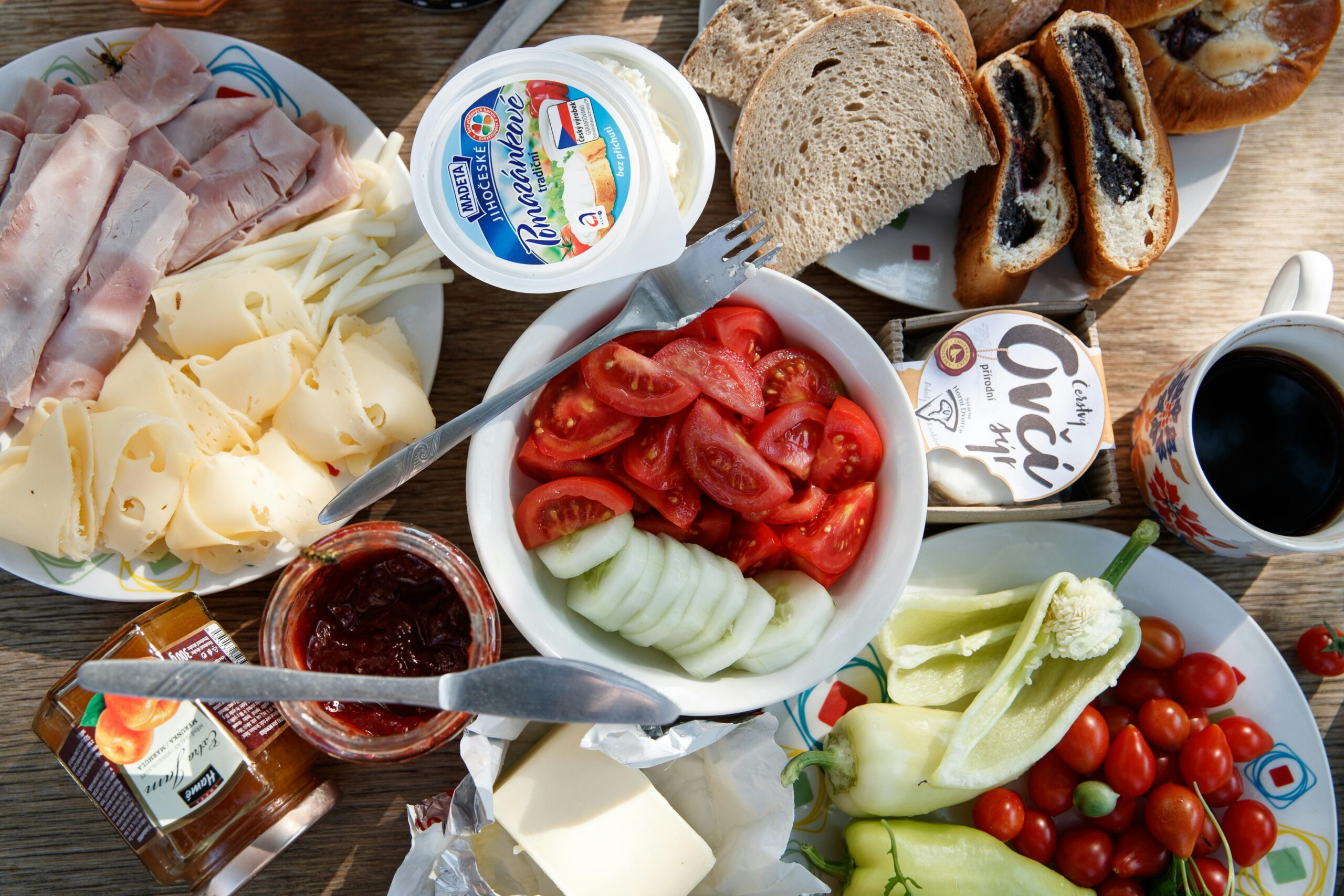 Delicious breakfast setup with cheese, cold cuts, bread, and fresh vegetables.